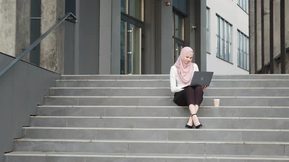 Young Muslim Woman Sitting on Stairs Near Business Center and Working on