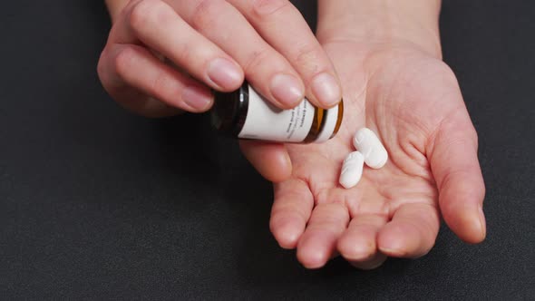Two Big White Round Pills Fall Into Palm of Hand From Pill Bottle