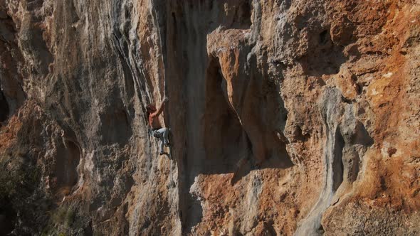 Slow Motion Aerial Drone Footage of Strong Man Rockclimber Climbing Up on Tough Hard Route on