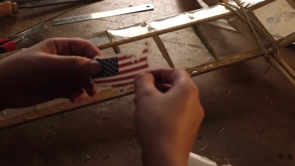 A Teenager Sticks a Sticker with the US Flag on the Wing of an Airplane