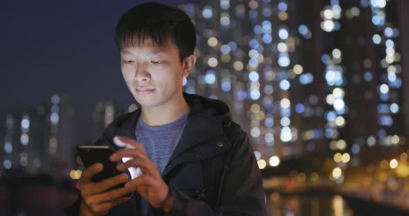 Asian man use of mobile phone in city in the evening