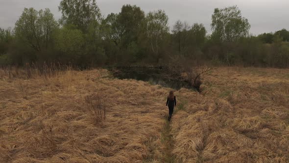 Woman in Protective Mask Goes By Path of Orange Grass