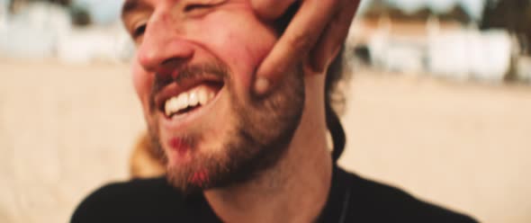 Hand of a man spreading sunscreen on a face of a friend at the beach