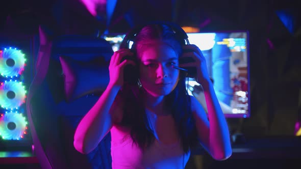 Young Woman with Pony Tails Playing a Game in Gaming Club - Put on Her Headphones and Turns