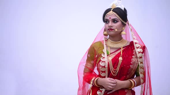 Sad and unhappy Indian Bengali bride against a white wall