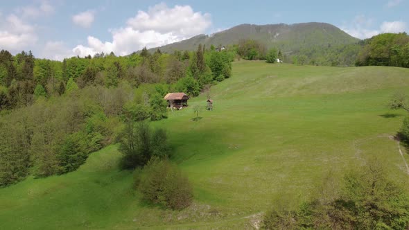 Green spring nature, old hay barn with hunting lookout beside, moving cloud shadow at hillside. Aeri