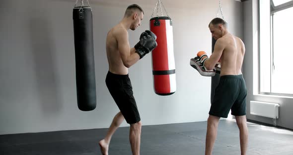 The Kickboxer is Practising His Middle Kick with Trainer in Slow Motion in the Gym Mixed Martial