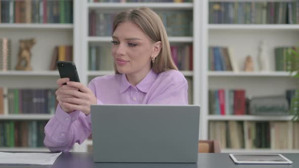 Woman Using Smartphone While Using Laptop in Office