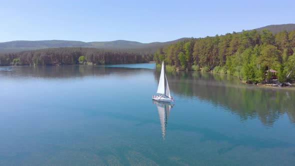 Aerial View of Sailing Boat Walking Alone on a Wide Blue Clear Lake on a Sunny Morning