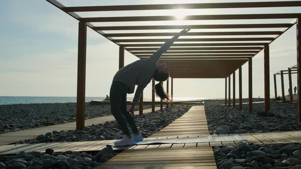 Sportswoman Is Making Chakrasana Exercise in Beach, Standing on Leg