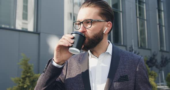 Man in Glasses Which Drinking Coffee Near Modern Urban Building while Going to His job