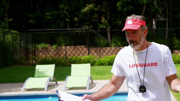 Lifeguard holding clipboard and whistling