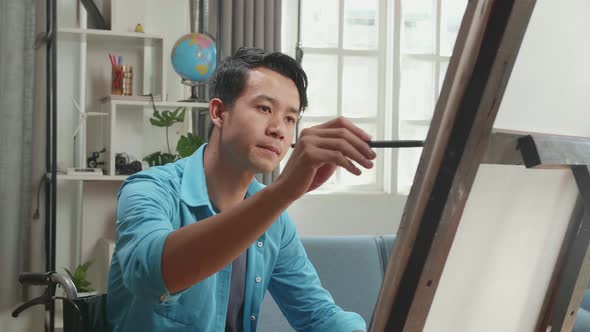 Asian Artist Man In Wheelchair Holding Paintbrush And Thinking Before Painting On The Canvas