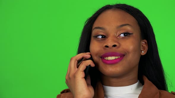 A Young Black Woman Talks on a Smartphone - Face Closeup - Green Screen Studio