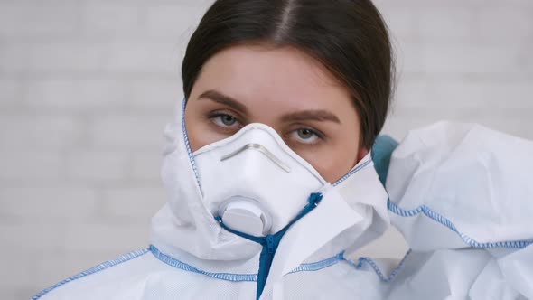 Doctor Taking Off Protective Hazmat And Mask After Work Indoor