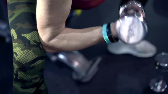 Middle-aged Strong and Independent Woman in Sportswear Pumping Hands Muscles Close-up with Dumbbells