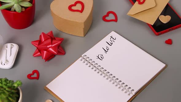 Zoom in of lettering TO DO LIST in a notebook near valentine's day card and present