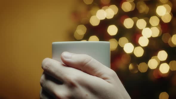 Hands hold cup with Christmas background