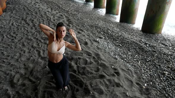 Extravagant Dance Performer Woman is Dancing on Sea Shore Under Pier Slow Motion