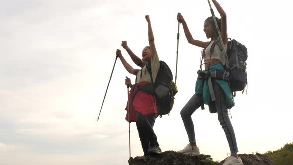 A group of trekkers with backpacks proudly arrive at the top of the mountain.