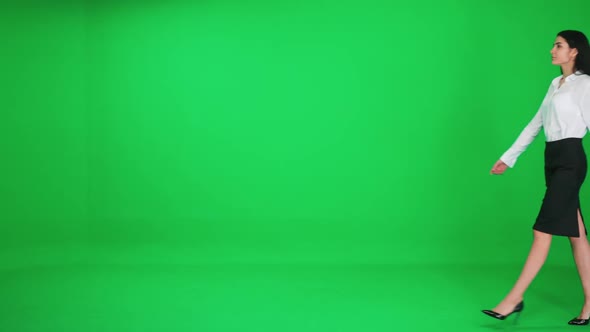 Young Businesswoman in a Suit Walks on a Green Background a Chromakey Template