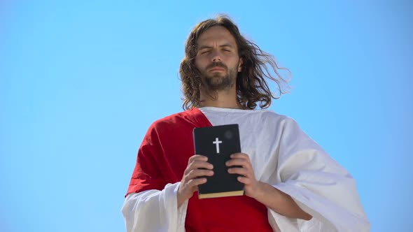 Strict God Holding Bible Against Blue Sky, Reminding of Faith and Repentance