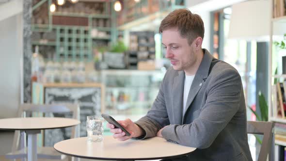 Attractive Young Man Using Smartphone in Cafe