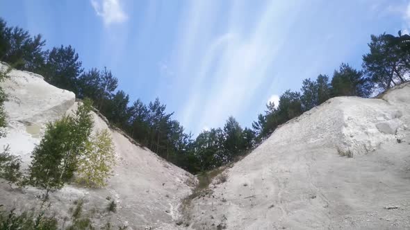 clouds fly over the slopes of chalk quarries with trees on top, time laps