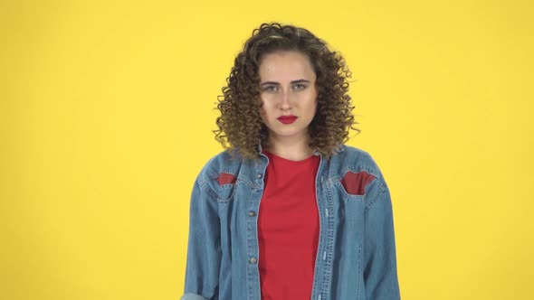 Woman Is Upset, Waving Her Hands in Indignation, Shrugs on Yellow Background at Studio, Slow Motion