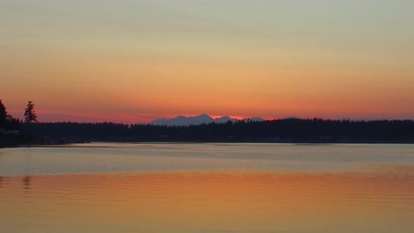 Time lapse and zoom out of sunset over the Olympic mountains seen from Fox Island, Puget Sound, Wash