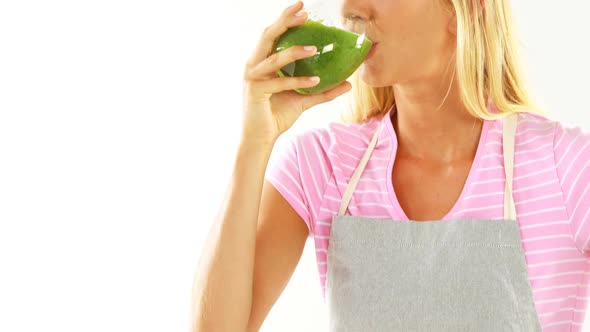 Smiling woman drinking vegetable smoothie against white background