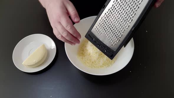 Hand of chef grating cheese on dish. Close up and high angle