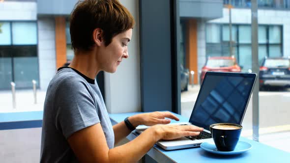 Businesswoman having a cup od coffee while using laptop