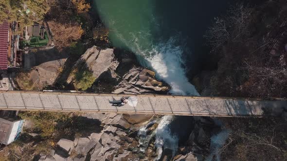 Newlyweds. Bride and Groom Lie on a Bridge Over a Mountain River. Aerial View