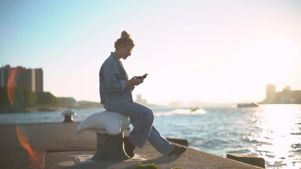 Slowmotion Side View of Charming Young European Woman with Blond Hair in Bun Sitting in Docks