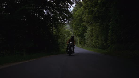 Motorcycle Wheel Traveling on the Gray Concrete Ground and View of Lush Forest