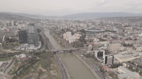 Flying over Kura river in Tbilisi. Beautiful aerial view of King Tamar bridge