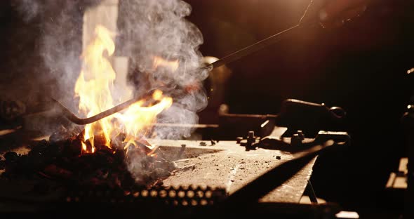 Hand of blacksmith heating iron rod in fire