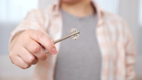Young Woman Does Opening Door Gesture Holding Key in Room