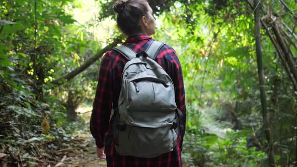 Young Woman with Backpack Walks in Lush Tropical Forest