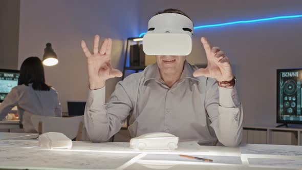 Middle-Aged Engineer in VR Goggles Working in Office