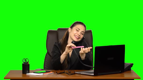 Girl at Workplace Is Working on Laptop, Talking on Two Phones and Sawing Nails. Green Screen