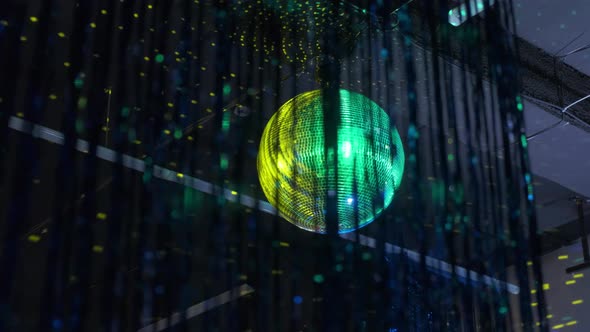 Colorful Yellow Green Mirrored Metallic Disco Ball Hanging in the Darkness