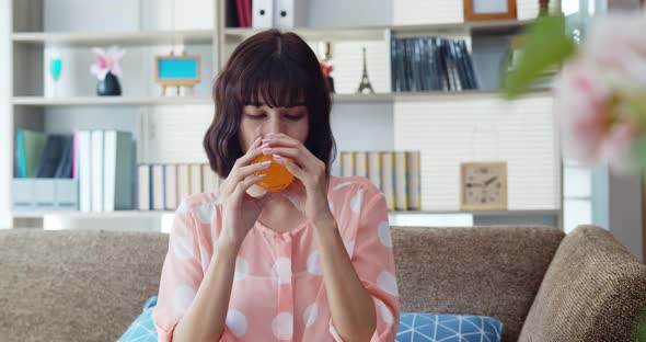 Asian young pretty woman drinking orange juice on sofa 