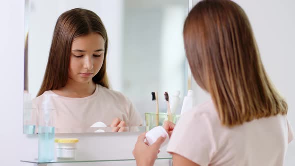 Teenage Girl Applying Moisturizer at Bathroom