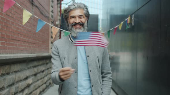 Slow Motion of Happy Grayhaired Man Waving American National Flag and Smiling Outdoors