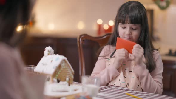 Charming Girl Kissing Letter to Santa Passing Red Folded Paper to Unrecognizable Woman