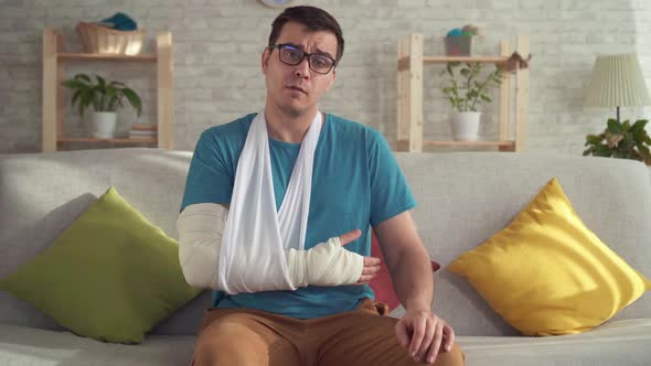 Portrait Sad Young Man in Glasses with Broken Arm