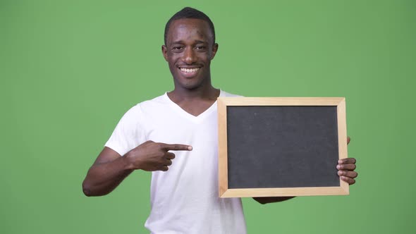 Young African Man Showing Blackboard and Giving Thumbs Up