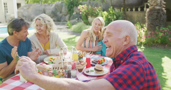 Happy caucasian family having dinner and taking selfie in garden